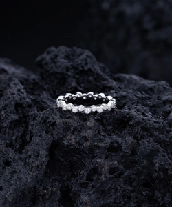 Détail d'une bague éternité sertie de zircons sur roche volcanique noire