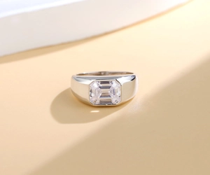 Close-up of polished silver wide band ring with large emerald cut clear zircon stone