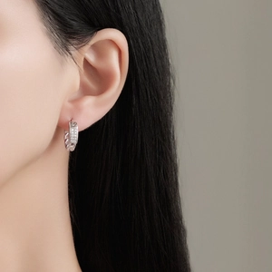 Boucles d'oreilles créoles géométriques en argent S925 avec zircons portées par un mannequin