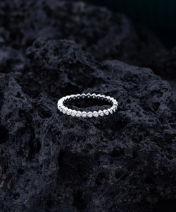 Macro view of S925 sterling silver wavy eternity ring with diamonds on volcanic rock