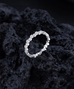 Gros plan d'une bague éternité sertie de diamants sur une roche volcanique noire