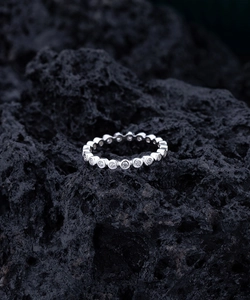 Détail macro d'une bague en argent sertie de zircons ronds sur fond de roche volcanique