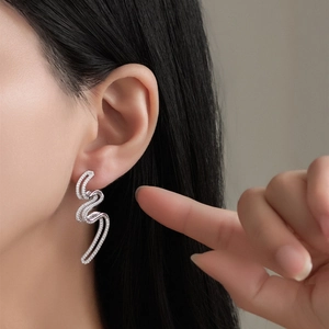 Boucles d'oreilles vagues en argent S925 serties de zircons portées par un mannequin