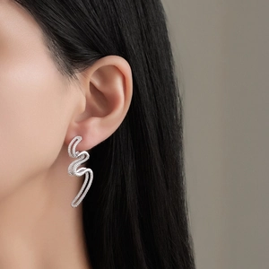 Élégantes boucles d'oreilles vagues en argent S925 avec zircons portées par modèle