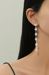 Detail of S925 silver fringe earrings with pavé heart accents on a female model