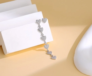 Detailed shot of asymmetric S925 silver heart tassel earrings with pavé diamond setting