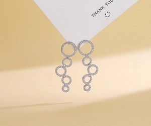 Detailed view of silver circular fringe earrings encrusted with sparkling cubic zirconia stones