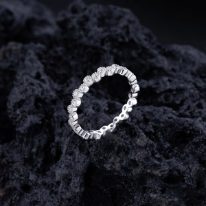Bague éternité minimaliste en diamants ronds sur un fond de pierre volcanique sombre