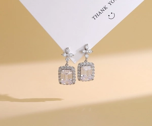 Macro shot of silver perfume bottle earrings with emerald cut cubic zirconia on a card