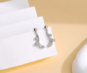 Detail of S925 silver flower tassel earrings with zircons on a white geometric stand