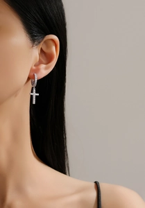Close-up of a model wearing silver cross drop earrings with micro-pave cubic zirconia