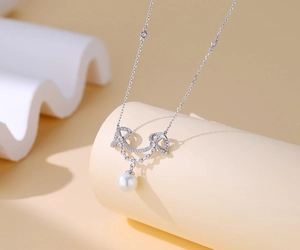 Macro shot of silver pearl necklace featuring a diamond-encrusted letter pendant design