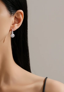 Close-up of S925 silver halo drop earrings with sparkling cubic zirconia on a model