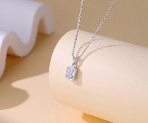 Macro shot of S925 silver necklace with emerald-cut cubic zirconia on beige pedestals