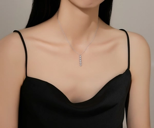 Close-up of minimalist S925 silver necklace with five vertical sparkling crystals on a model