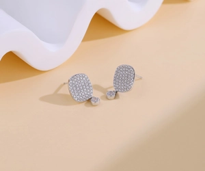Close-up of S925 silver stud earrings featuring micro-pave rectangular zircons and round drops