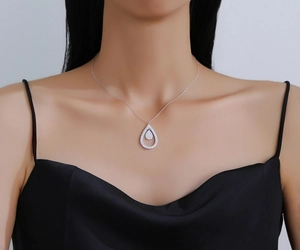 Close-up of a silver double teardrop pendant necklace with pavé crystals on a model