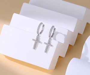 Detailed view of S925 silver cross earrings with micro-set zircon on beige background