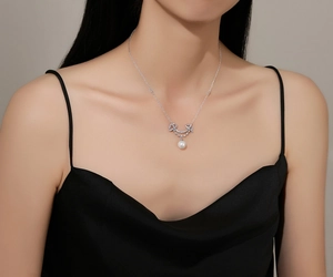 Close-up of S925 sterling silver smile necklace with pearl and diamonds on female neck