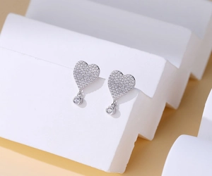 Detail view of heart-shaped S925 silver stud earrings with pavé crystals and round pendants