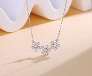 Vue macro de trois pendentifs marguerites sertis de pavés sur une fine chaîne en argent S925
