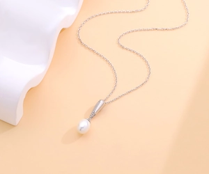 Elegante collana con ciondolo in argento s925 con perla e diamanti su sfondo caldo