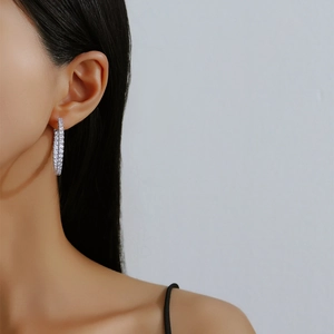 S925 sterling silver moissanite hoop earrings worn by a model on a grey background
