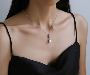 Elegante ciondolo di perla a goccia con dettagli in diamanti argentati su una modella