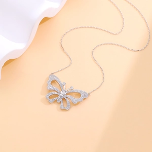 Elegant silver butterfly necklace with sparkling pavé cubic zirconia on orange background
