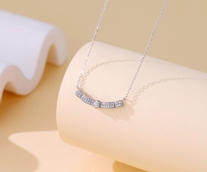 Close-up of S925 sterling silver necklace with curved pavé diamond pendant on props