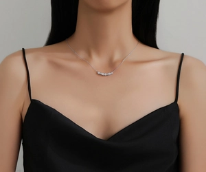 S925 sterling silver necklace detail with curved diamond pendant on a model neck