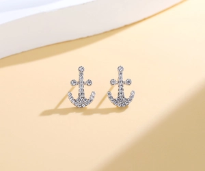 Macro shot of silver S925 anchor stud earrings with micro-pave crystals on dual-tone background