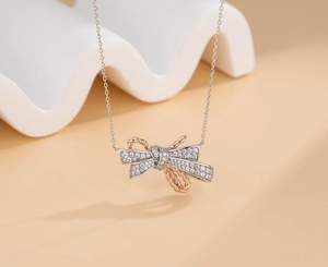 Macro shot of bicolor silver bow pendant featuring pave zircons and rose gold details