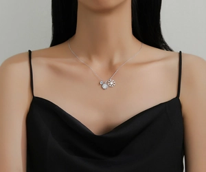 Detail of silver double snowflake necklace with blue gemstone on model in black dress