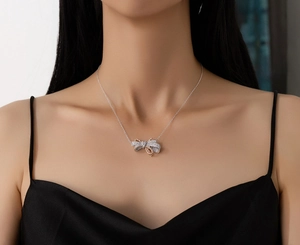 Detail of S925 silver bow necklace with pave diamonds and rose gold accents on model