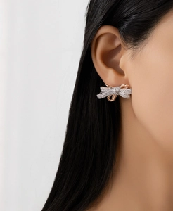 Macro view of two-tone S925 sterling silver bow earrings with pave crystals on model