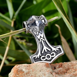 Vintage Mjölnir pendant necklace with Viking engravings on a rustic brick background