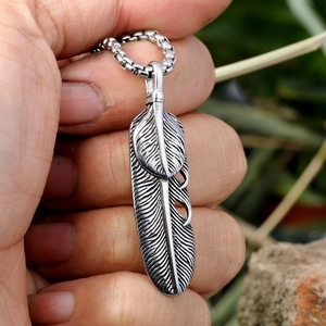 Détail de pendentifs plume en argent vintage avec texture métallique tenue à la main