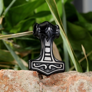 Macro detail of Nordic Viking Mjölnir pendant with black enamel on a rustic brick background