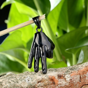 Vue rapprochée d'un pendentif noir unique en forme de geste de main en décor naturel