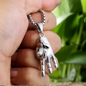 Détail d'un pendentif main argentée avec chaîne gourmette tenue à la main