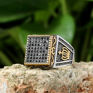 Detailed view of silver signet ring with black crystals and gold crown relief