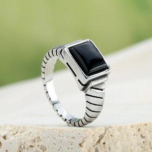 Macro view of a men's silver stainless steel ring with rectangular black gemstone inlay