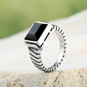 Macro view of men's signet ring with rectangle black stone and tiered texture band