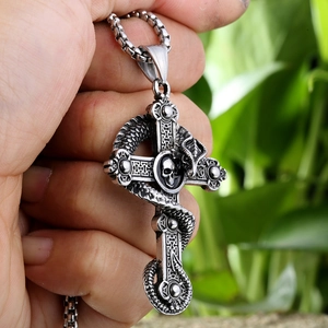 Vue macro d'un pendentif croix en acier rétro avec motif de serpent et tête de mort