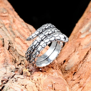Macro shot of silver snake ring showing intricate scale textures on a bark background
