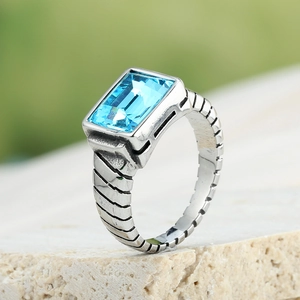 Close-up of vintage stainless steel ring with rectangular blue gemstone and textured band