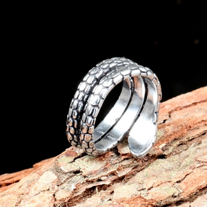 Vintage titanium steel snake ring with textured scale pattern on dark wood bark
