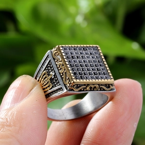 Macro view of square signet ring featuring black stones and golden crown detailing