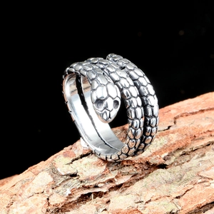 Detailed view of snake-shaped titanium steel ring with realistic scales on tree bark